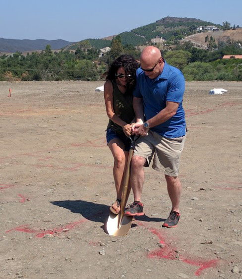 Husband and wife, holding golden shovel to signify breaking ground on new custom home lot in Temecula